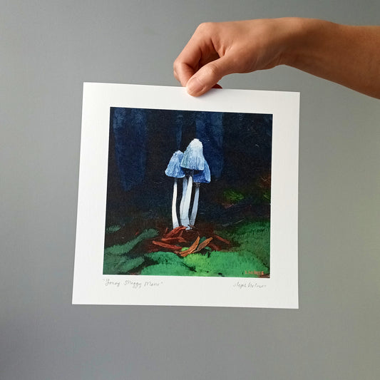 A photo of a hand holding an art print of a young shaggy mane mushroom.