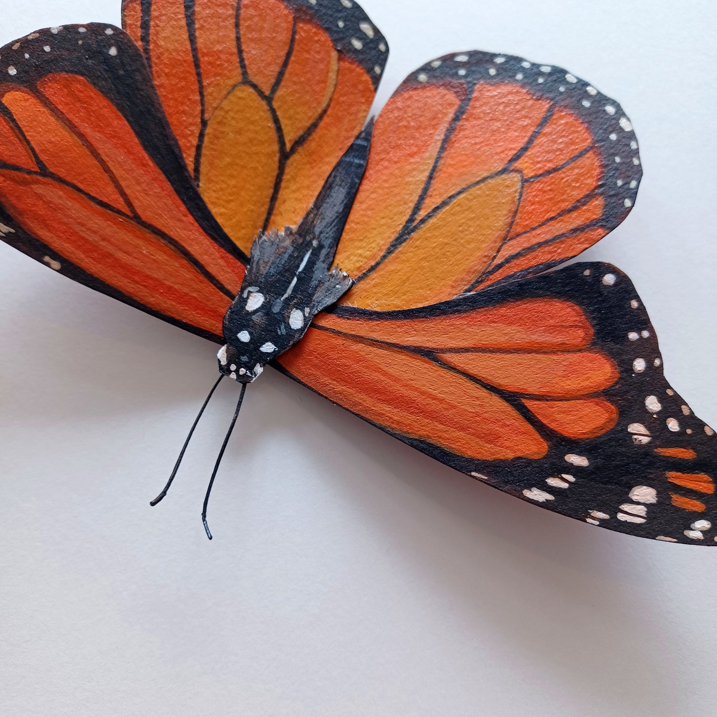 An orange monarch butterfly sculpture sits on a white table.