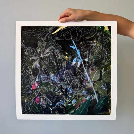 A hand holding an art print featuring a dark forest outlined in white chalk.