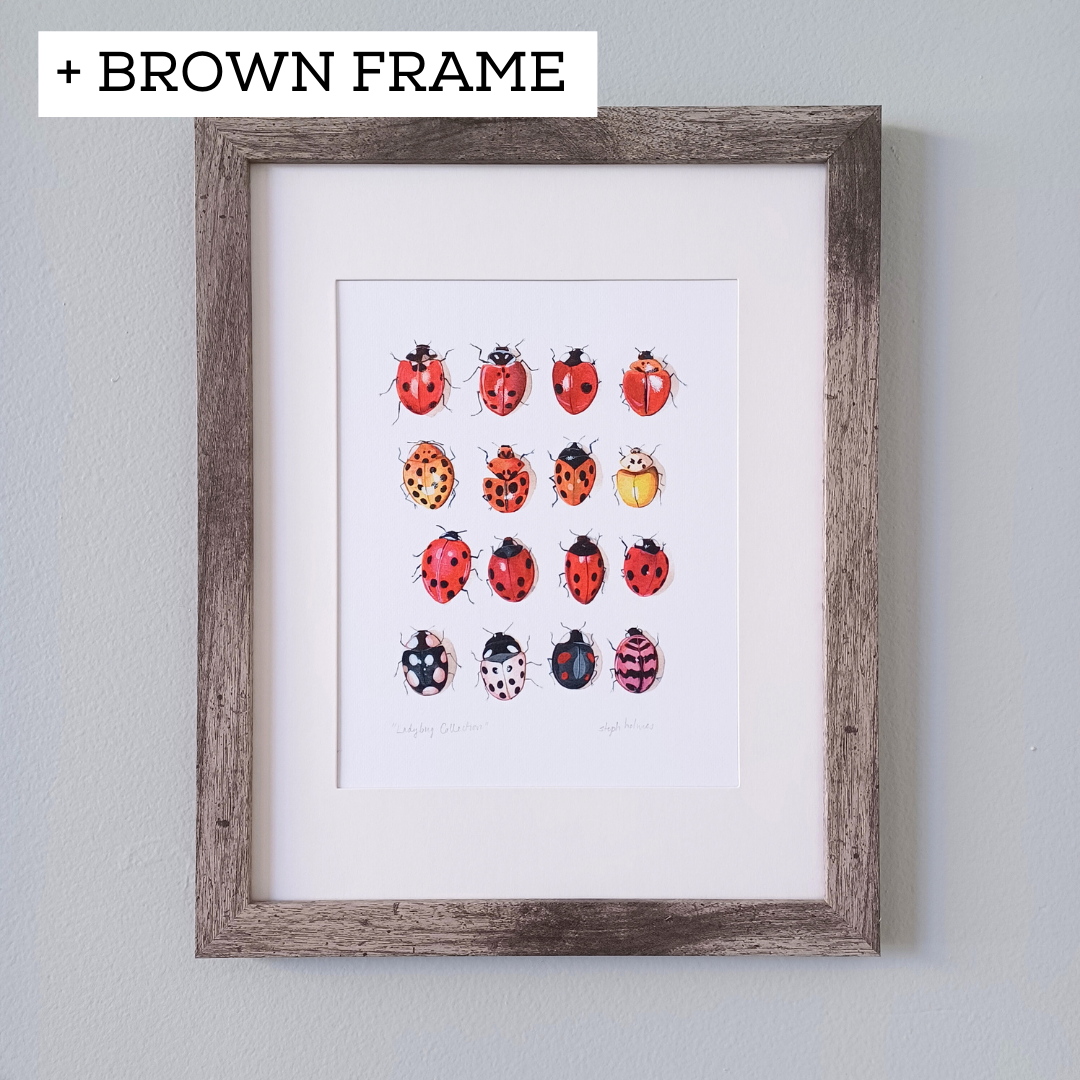 A photo of the ladybug art print framed and hanging on a gray wall.